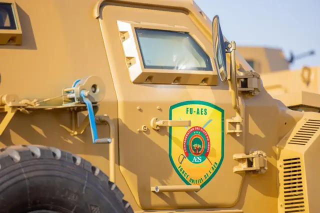A military vehicle with a yellow background displaying a 'FU-AES' sign.