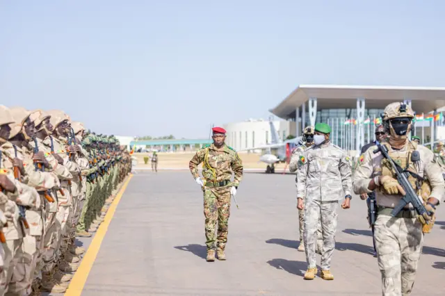 General Assimi Goita, Mali's transitional president in military uniform with a green beret and face mask, reviewing troops during a parade.