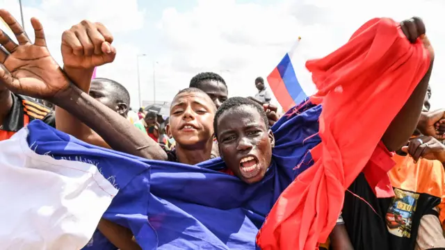 A man wrapped in a russian flag waves arms and shouts as supporters of Niger's military leaders gather at nigerien and french air bases in Niamey