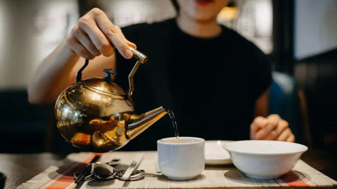 Une femme verse de l'eau chaude dans une tasse