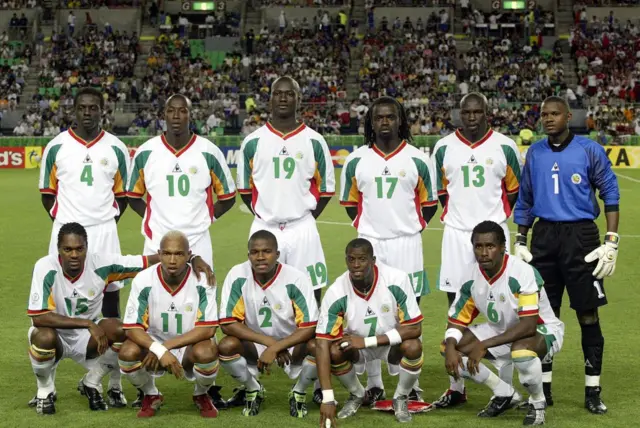 L'équipe du Sénégal pose avant le quart de finale de la Coupe du Monde de la FIFA 2002 à la Turquie au stade Nagai d'Osaka le 22 juin 2002 à Osaka, au Japon : Pape Malick Diop, Khalilou Fadiga, Papa Bouba Diop, Ferdinand Coly, Lamine Diatta, Tony Sylva, (fr) Salif Diao, El Hadji Diouf, Omar Daf, Henri Camara, Aliou Cissé 