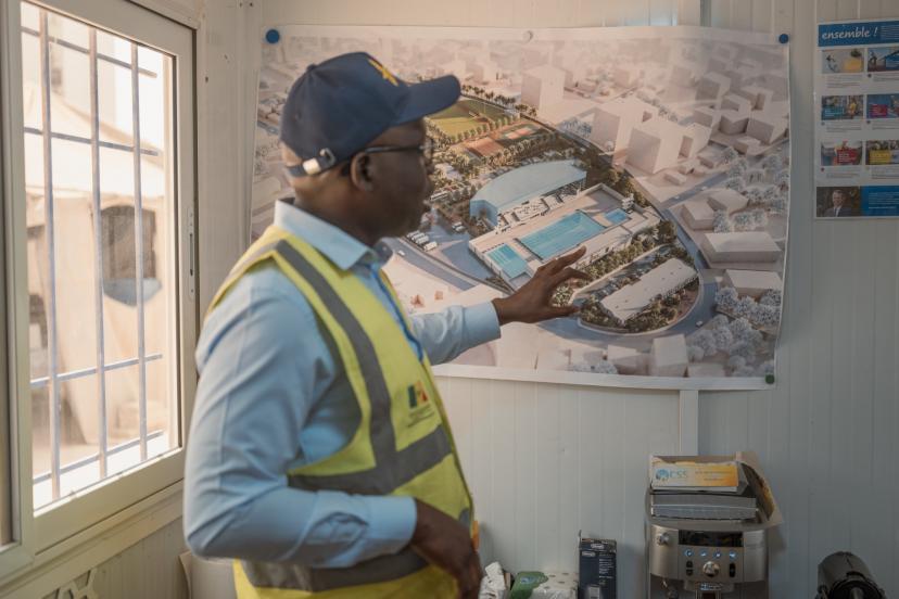Babacar Senghor, coordonnateur du projet des Jeux Olympiques de la Jeunesse (JOJ), devant les plans de la piscine. (S.&nbsp;Cherkaoui/L'Équipe)